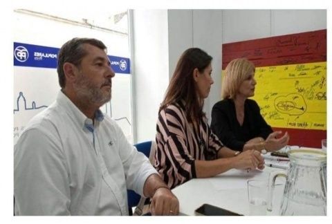 Los diputados y la portavoz del PP local con el tablón donde se lee la frase en la sede del PP de Rota