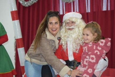 Papá Noel tomándose una foto con una niña y su madre
